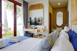 a bedroom with a bed and a desk and a television at เดอะซีน คาบาน่า บีช รีสอร์ท ขนอม The Scene Cabana Beach Resort Khanom in Ban Plau