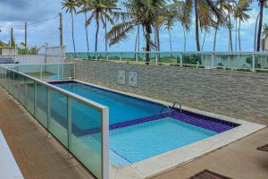 a large swimming pool with a brick wall and palm trees at Porto de Galinhas Pé na Areia Belize in Porto De Galinhas