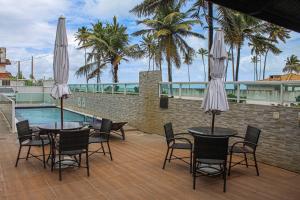 a patio with two tables and chairs with umbrellas at Porto de Galinhas Pé na Areia Belize in Porto De Galinhas