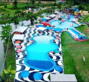 菲格雷多总统镇Chalé Amazon Aqua Park的水上乐园的游泳池，人们躺在草地上