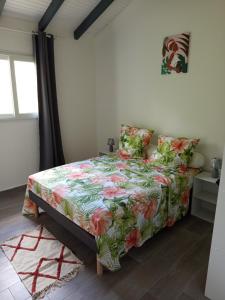 a bedroom with a bed with a floral bedspread at Villa Lilisse in Le Moule