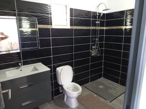 a black tiled bathroom with a toilet and a shower at Villa Lilisse in Le Moule +2 photos