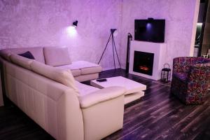 a living room with a white couch and a fireplace at Vladana DELUXE App 2 in Kruševac