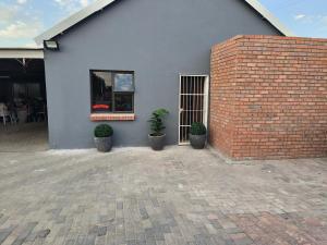 韦尔科姆Acama Guest House的一栋有盆栽和窗户的蓝色建筑