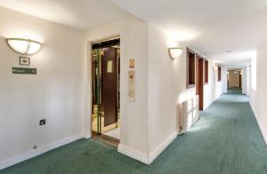 a hallway with white walls and green carpet at ROYAL Apartment in HARRODS in London