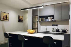 a kitchen with a white counter and some chairs at INEZA SUITEs in Kampala