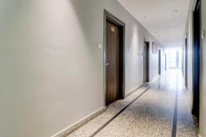 a hallway with white walls and a wooden door at Super Hotel O Gold Inn in Rohtak