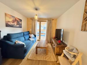 a living room with a blue couch and a tv at AO Duplex 82 m2 in Vars