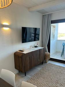 un soggiorno con una TV a schermo piatto su una parete di TheView108, Rena Bianca a Baja Sardinia