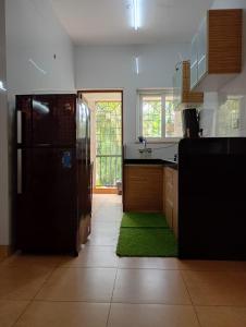 eine Küche mit Kühlschrank und grünem Teppich in der Unterkunft Heritage Exotica 2BHK Apartment service apartments in goa in Arpora