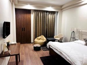 a bedroom with a bed and a desk and a window at PrimeStays Omaxe ITC, Greater Noida in Greater Noida