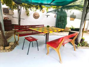 a picnic table and two benches under a tent at Самостоятелна къща за гости Трояна in Troyan