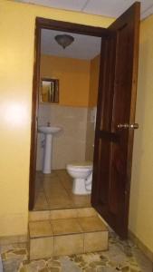 a bathroom with a toilet and a sink at Hotel Senderos Maya in San Pedro Sula