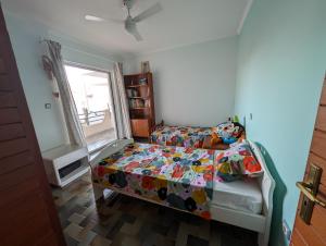 Un dormitorio con una cama con un edredón colorido y una ventana en Family apartment mountain and sea, en Atenas