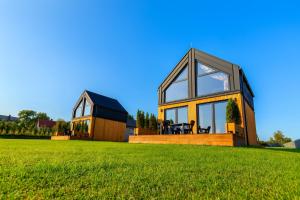 a house on a grassy field with a building at Domki Baby Jagi in Krajno Pierwsze