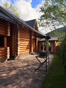 a log cabin with a grill outside of it at Над рікою Міжгірʼя in Mizhhirʼʼya