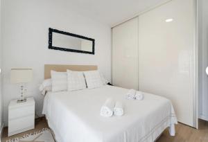 a white bedroom with a large white bed with two white towels at Sun Garden in Adeje