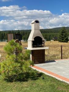 a outdoor pizza oven in a field with a fence at Topli kutak Golija in Novi Pazar