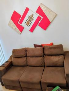 a living room with a brown couch and books on the wall at Flat aconchegante e tranquilo in Campos dos Goytacazes
