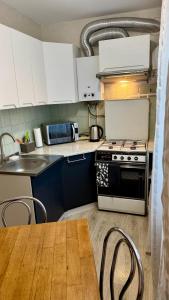 a kitchen with a stove and a table with chairs at Апартаменти в центрі міста in Luts'k