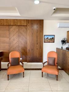 two orange chairs in a waiting room with wood panels at Amchit Grand Hotel in Al Qarfī
