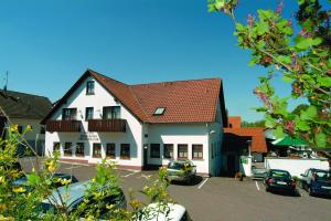 ein Gebäude mit Autos auf einem Parkplatz in der Unterkunft Landgasthof Lang Zum Adler in Oberkalbach