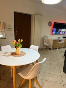 una mesa blanca y sillas con un jarrón de flores. en Cozy apartment 5 min to the sea and airport, en Isola Sacra