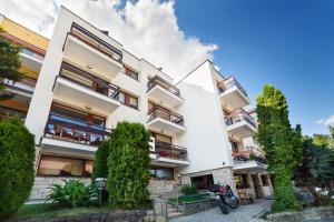 an apartment building with trees in front of it at Beskid Balans & SPA in Krynica Zdrój