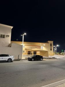 タブークにあるشقة السيف خلف مجمع الغرويの夜間の建物の前に駐車した車2台