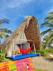 une cabane au toit de chaume avec un hamac et des palmiers dans l'établissement Portoalegre del hamaquero, à Puerto Escondido