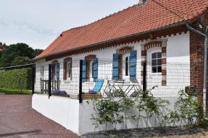 een wit huis met blauwe ramen en een hek bij Ferme du lin : Angelin in Gueschart