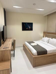 a bedroom with a bed and a desk and a television at Adar Hotel in Lagos