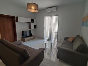 a living room with two couches and a television at Modern 2BR Apartment - Close to Gozo Ferry in Għajnsielem