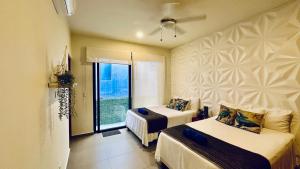 ein Hotelzimmer mit zwei Betten und einem Fenster in der Unterkunft Lunada PH with Private Rooftop and Jacuzzi by Caribe Rentas in Playa del Carmen + 85 Fotos