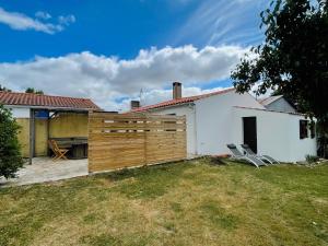 a house with a fence and two chairs in a yard at Maison proche de la Mer ! in Grues