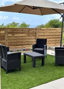 a patio with a table and chairs and an umbrella at Maison du plateau - Horizon Caraïbes in Vieux-Habitants