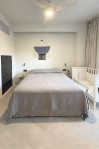 a white bedroom with a bed and a chair at Nikiti Blue house 30m from the beach with sea view in Nikiti