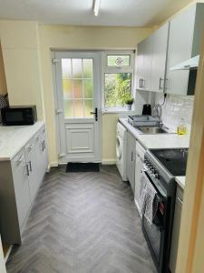 una cocina con fregadero y estufa horno superior en Spacious 3 Bedroom house in Luton with free on-street parking, Close to Airport and Town Centre, en Luton 13 fotos más