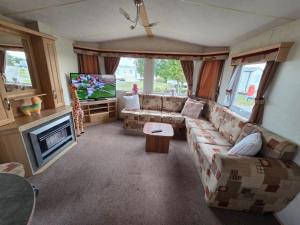 Saint OsythにあるSt Osyth, Clacton-on-sea, Cozy Beach side Caravan, Wifi, Tea and Coffee, Parking includedのソファとテレビのあるリビングルーム