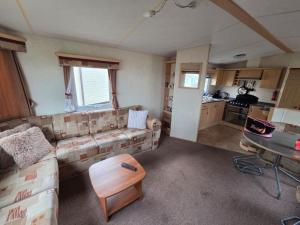 a living room with a couch and a table at St Osyth, Clacton-on-sea, Cozy Beach side Caravan, Wifi, Tea and Coffee, Parking included in Saint Osyth