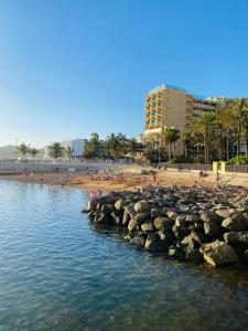 a beach with a group of people and a building at BEACH Arguineguin SEA VIEW 6 CHG FAMILY HOTEL in Arguineguín