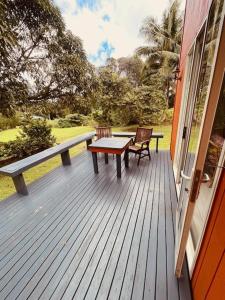 eine Holzterrasse mit einem Tisch und Stühlen auf einem Haus in der Unterkunft Mango Grove Cottage in Rarotonga + 2 Fotos