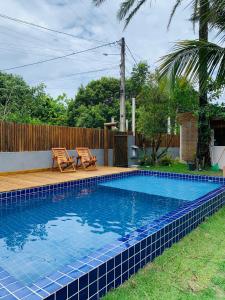 a swimming pool in a yard with two chairs next to it at Suíte 3 Privativa Taipu de Fora in Barra Grande