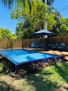 a swimming pool in a yard with chairs and an umbrella at Suíte 3 Privativa Taipu de Fora in Barra Grande +5 photos