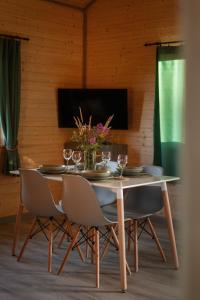 a dining room table with chairs and wine glasses at Domki Sudecka Przystań in Duszniki Zdrój
