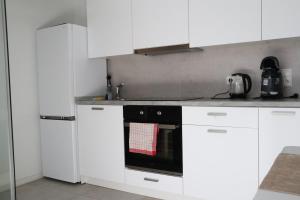 una cocina con armarios blancos y horno negro en RheinMosel Wellness 11, en Coblenza