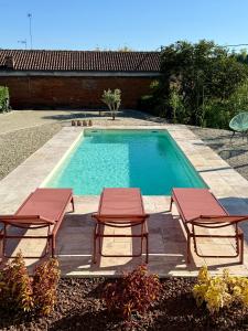 a swimming pool with two picnic tables and two chairs at Casa MIA - tra Monferrato, Langhe e Roero in CastellʼAlfero