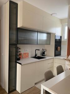 una cocina con armarios blancos y electrodomésticos negros en Résidence du centre 8, en Kragujevac