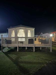 a large white house with a porch at night at Pebble Breeze in Ingoldmells