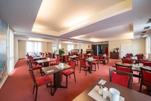 un comedor con mesas y sillas rojas en Hotel Vater Rhein, en Wörth am Rhein